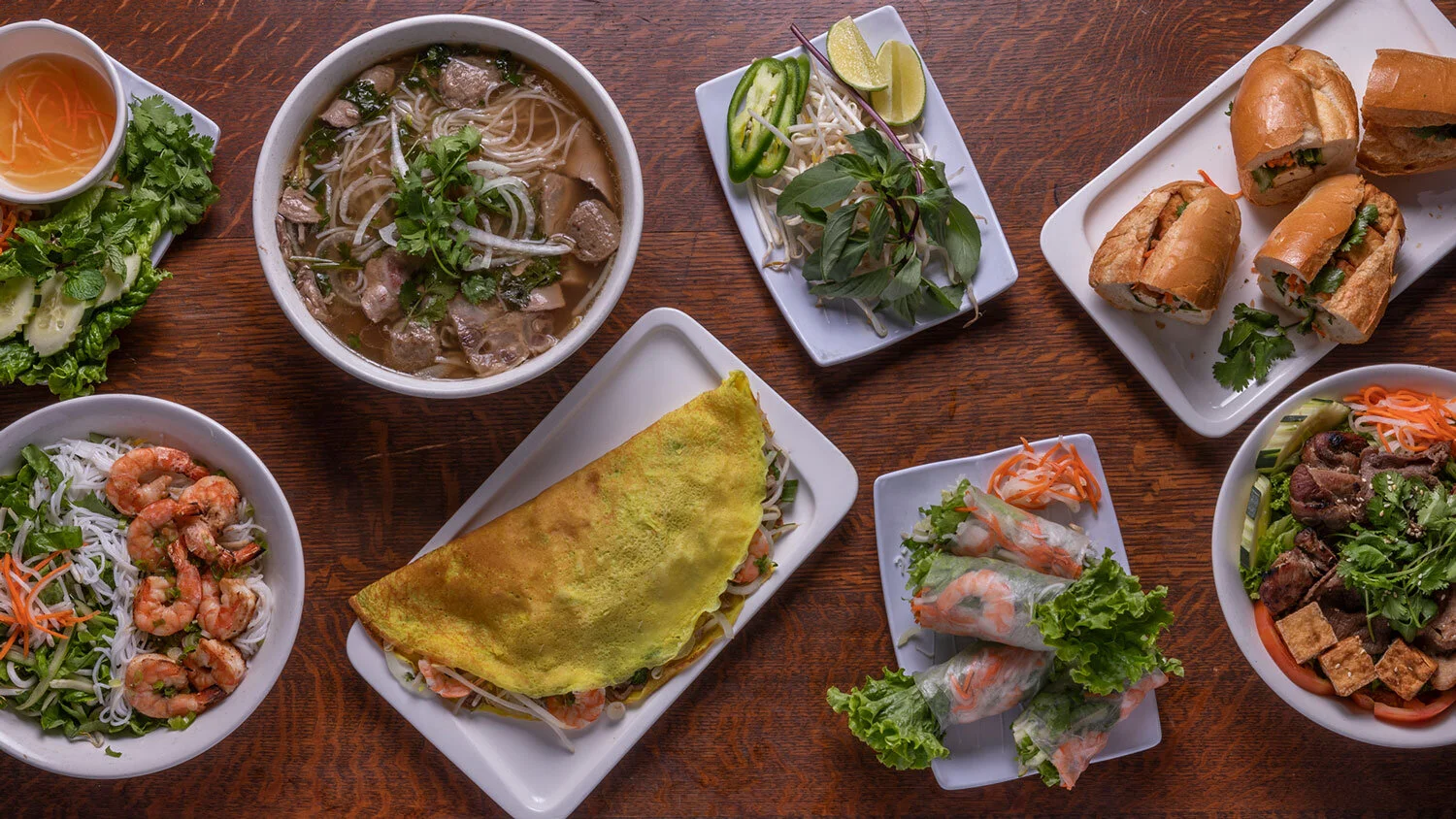 Monster Pho table spread: pho, banh xeo, spring rolls, banh mi, vermicelli bowls and fresh herbs