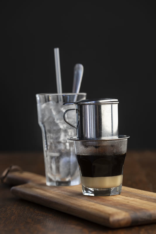 Vietnamese phin filter coffee dripping over condensed milk